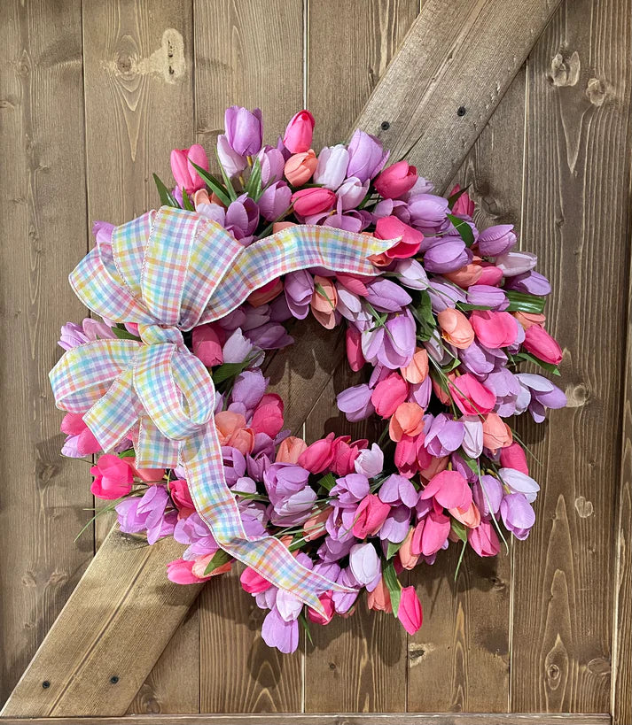Colorful tulip wreath with a plaid ribbon on a wooden door