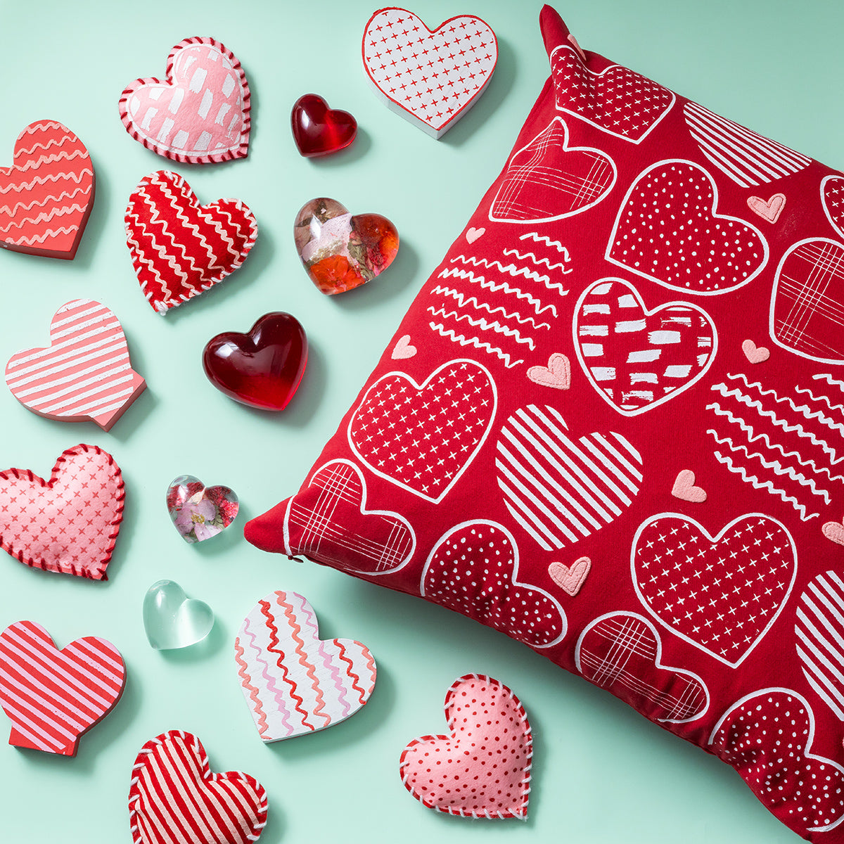 Red pillow with heart patterns on a light blue background with decorative heart-shaped objects.