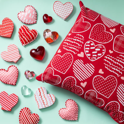 Red pillow with heart patterns on a light blue background with decorative heart-shaped objects.