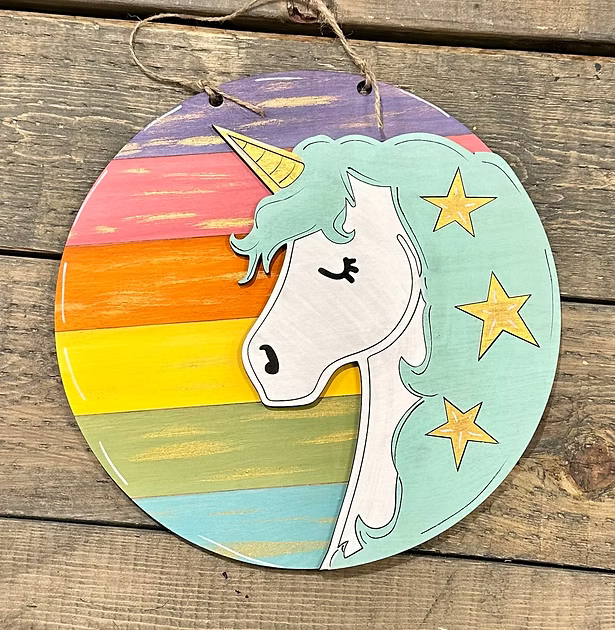 Round wooden ornament with unicorn design and rainbow gradient on a wooden surface