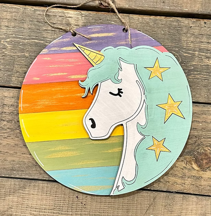 Round wooden ornament with unicorn design and rainbow gradient on a wooden surface
