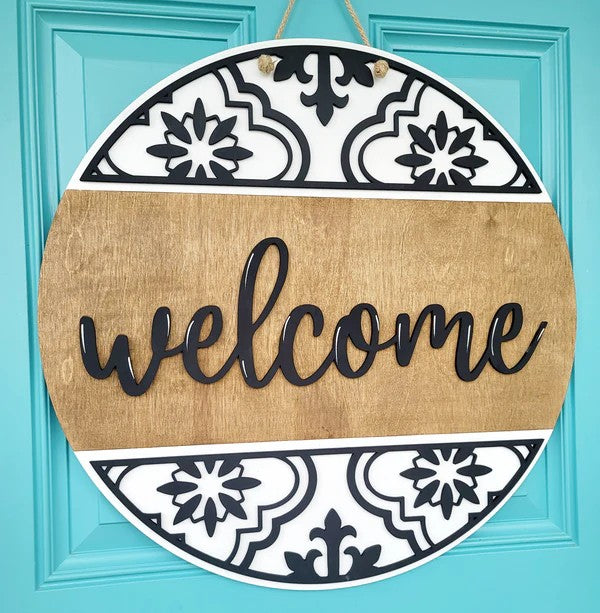 Decorative 'welcome' sign with black and white patterns on a turquoise door.