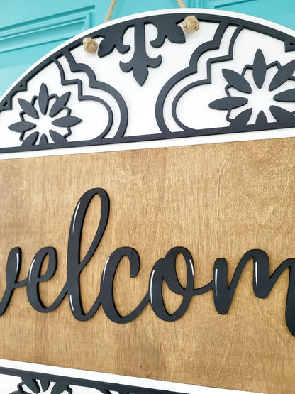 Decorative 'welcome' sign with intricate patterns on a light blue background