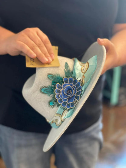 Person holding a decorative hat with floral embroidery