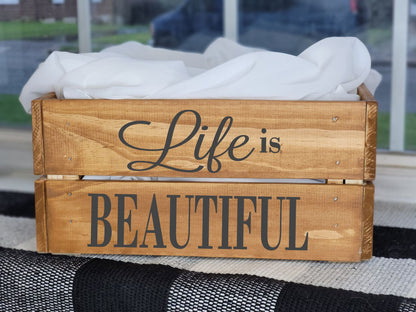 Wooden crate with 'Life is Beautiful' text on a black and white checkered rug.