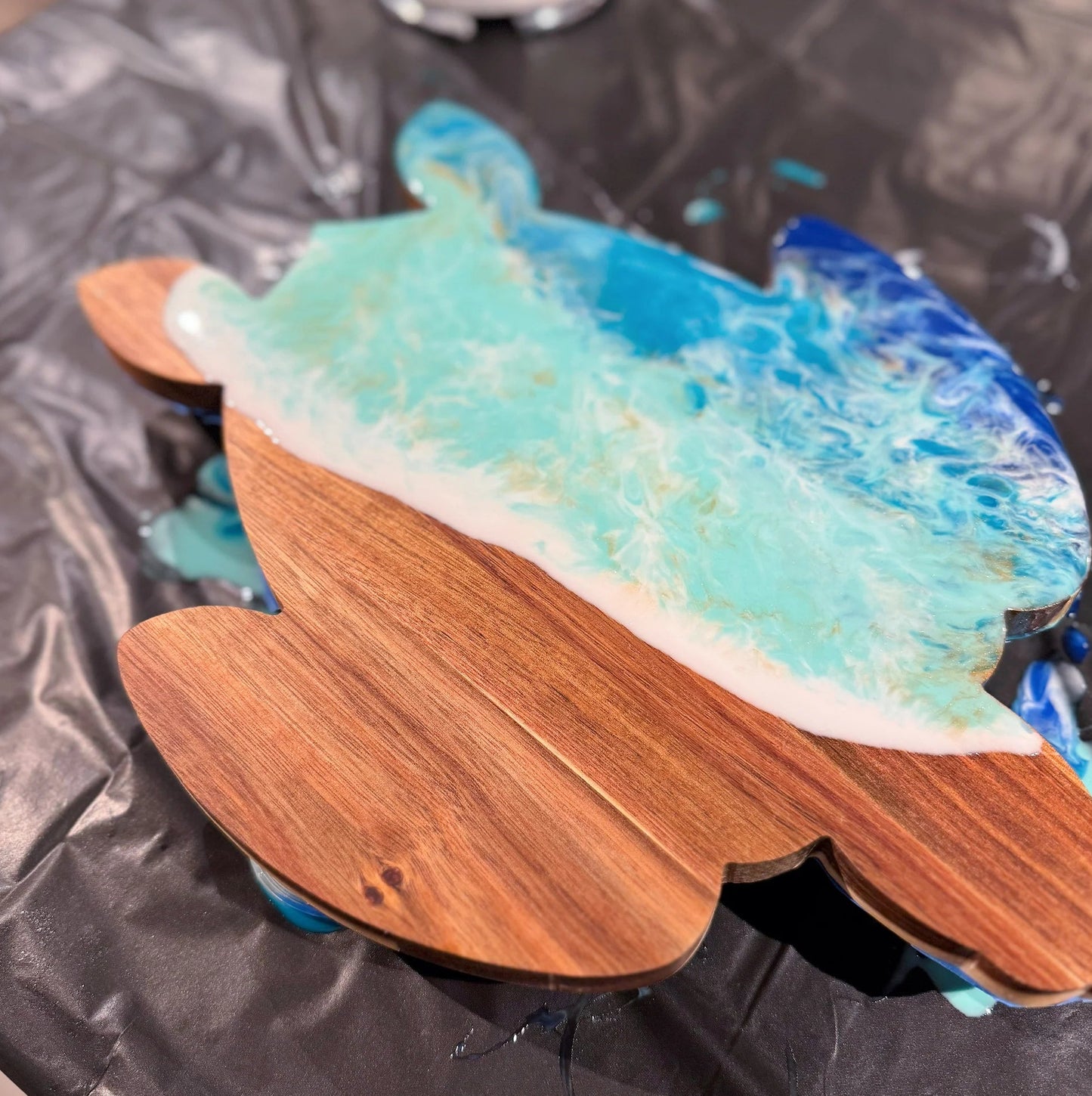 Wooden surfboard-shaped object with blue and white design on a black surface